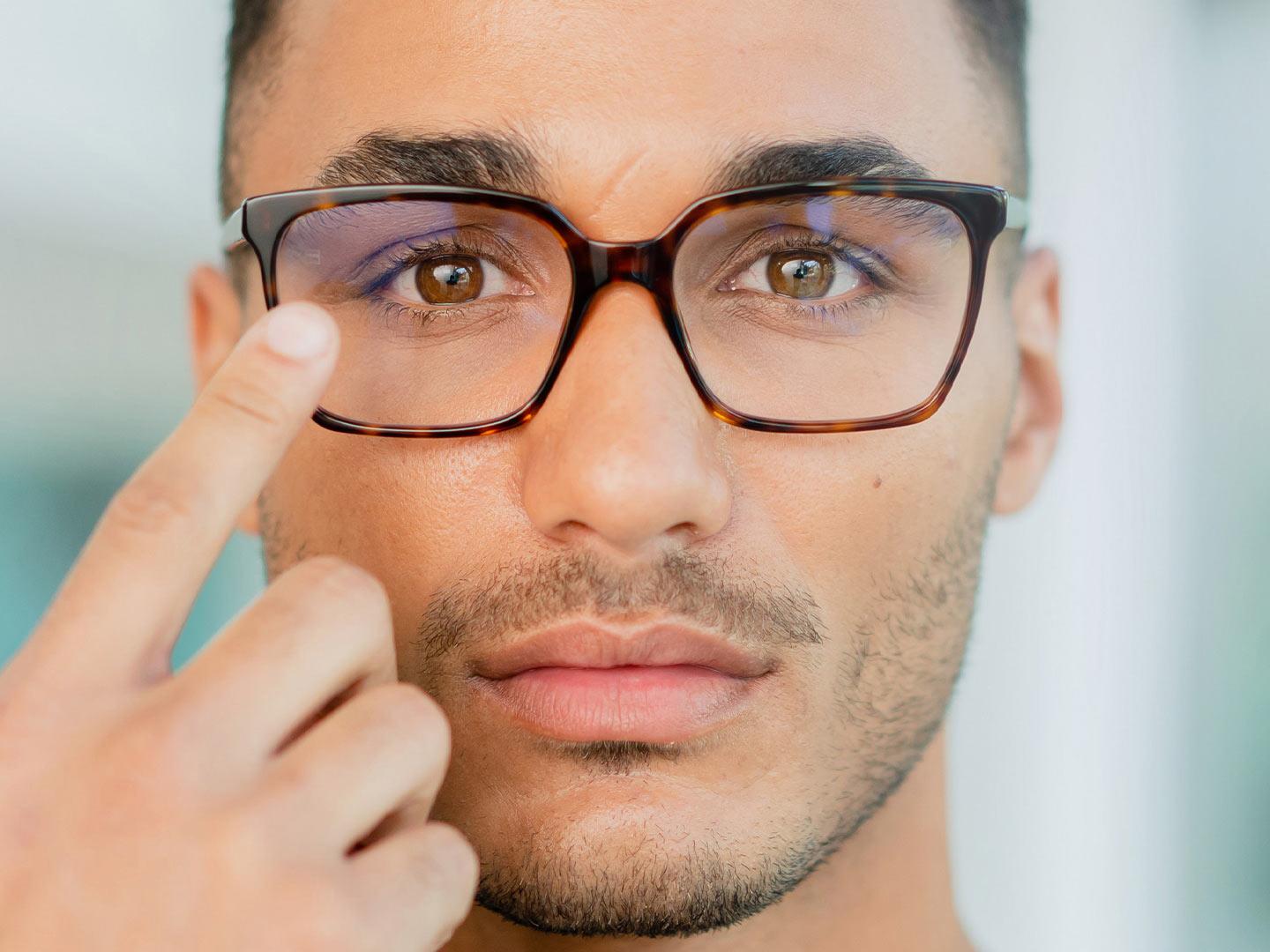 Gözlüklerinin yüzeyine dokunan gözlüklü bir adam