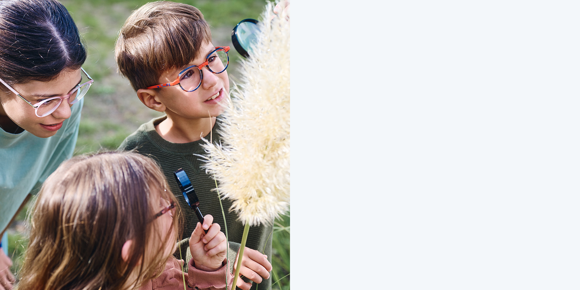 ZEISS MyoCare gözlük camları kullanan 2 kız ve 1 erkek çocuk. Bir bitkiye bakıyorlar, üç çocuktan ikisi bitkiye büyüteçle bakıyor.