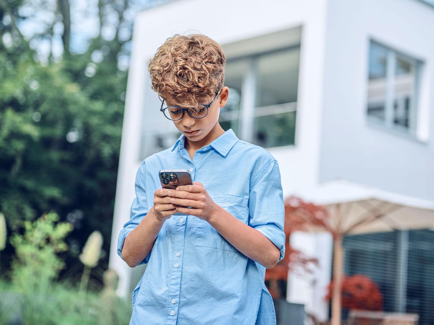 Dışarıda telefonuna bakan genç bir erkek çocuk.