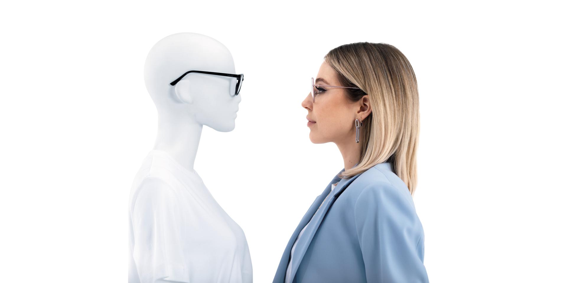 ZEISS ClearView gözlük takan kadın, gözlük takan mankenin karşısında duruyor.