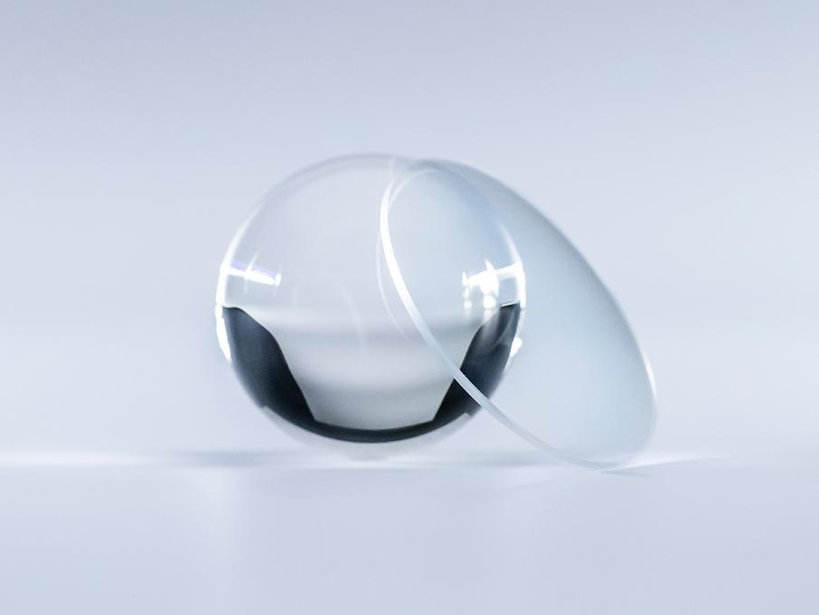 ZEISS Platinum kaplamalı bir lens, yanındaki cam küreye kıyasla hiçbir yansıma olmadan kristal berraklığındadır.