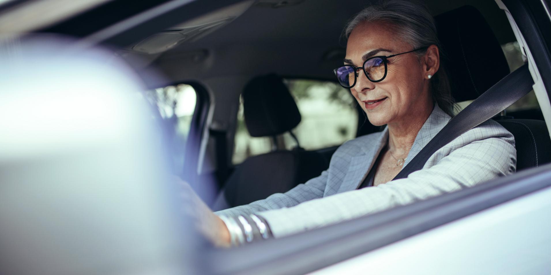 Arabadaki olgun bir kadın ZEISS DriveSafe camlı gözlük takıyor.