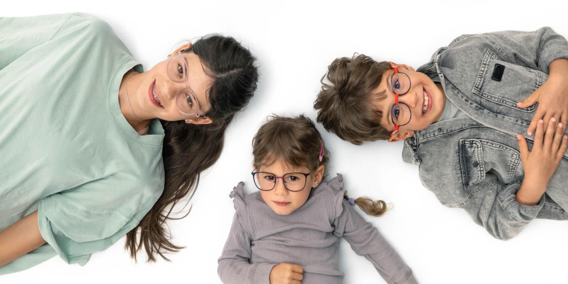 ZEISS Miyop camları takan bir genç ve iki küçük çocuk yerde yatıyor.