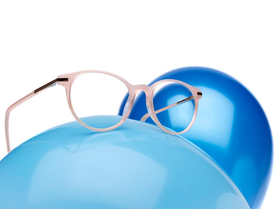 Mavi balon üzerinde ZEISS MyoCare camlı pembe gözlük çerçevesi.
