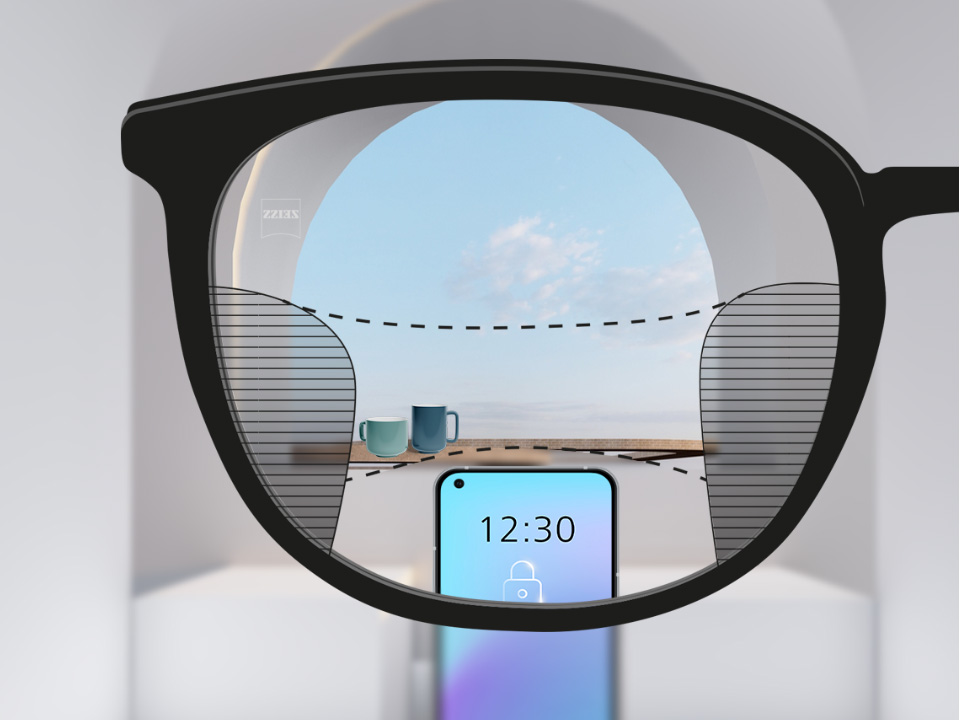 Arkaplanda akıllı telefon ve bardaklar bulunan ZEISS Progressive SmartLife lensli bir bakış açısı görüntüsü, lens tamamen şeffaf ve sağda ve solda ince bulanık çizgiler var.